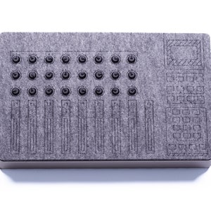 Può includere: Un pannello acustico in feltro grigio con un design stampato di una console di missaggio, con manopole, cursori e pulsanti.