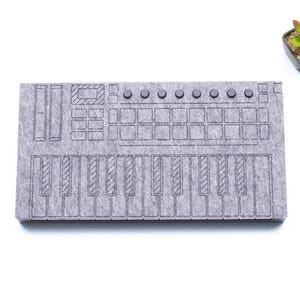 Pode incluir: Um tapete de rato de feltro cinzento com um contorno preto de um teclado e um pad de bateria. O tapete de rato é projetado para se parecer com um controlador de produção musical.