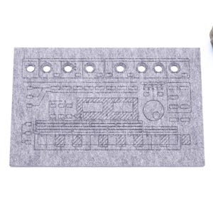 Peut inclure: Un tapis de souris en feutre gris avec un contour noir d'un clavier de synthétiseur. Le tapis de souris a plusieurs trous pour la gestion des câbles.