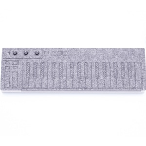 Puede incluir: Un teclado de fieltro gris con un contorno negro de las teclas y los botones. El teclado está sobre una superficie blanca.