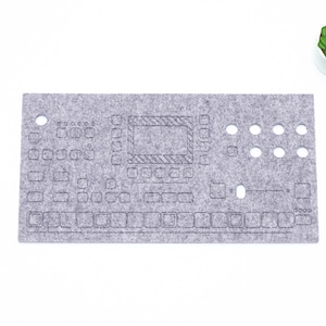 Peut inclure: Un tapis de clavier en feutre gris avec un contour noir d'un clavier et de commandes. Le tapis a un petit trou dans le coin supérieur gauche et le mot "loop" dans le coin inférieur droit.