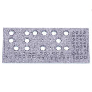 May include: A grey felt panel with cutouts for knobs, buttons, and other electronic components. The panel is designed for use with a synthesizer or other electronic music equipment.