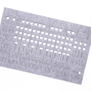 May include: A gray felt panel with cut-out shapes resembling a sound mixing console. The panel has numerous circular and rectangular openings, along with slider-shaped cutouts. A small potted plant is in the upper right corner. The text "WaveTable 2025" is in the lower right corner.