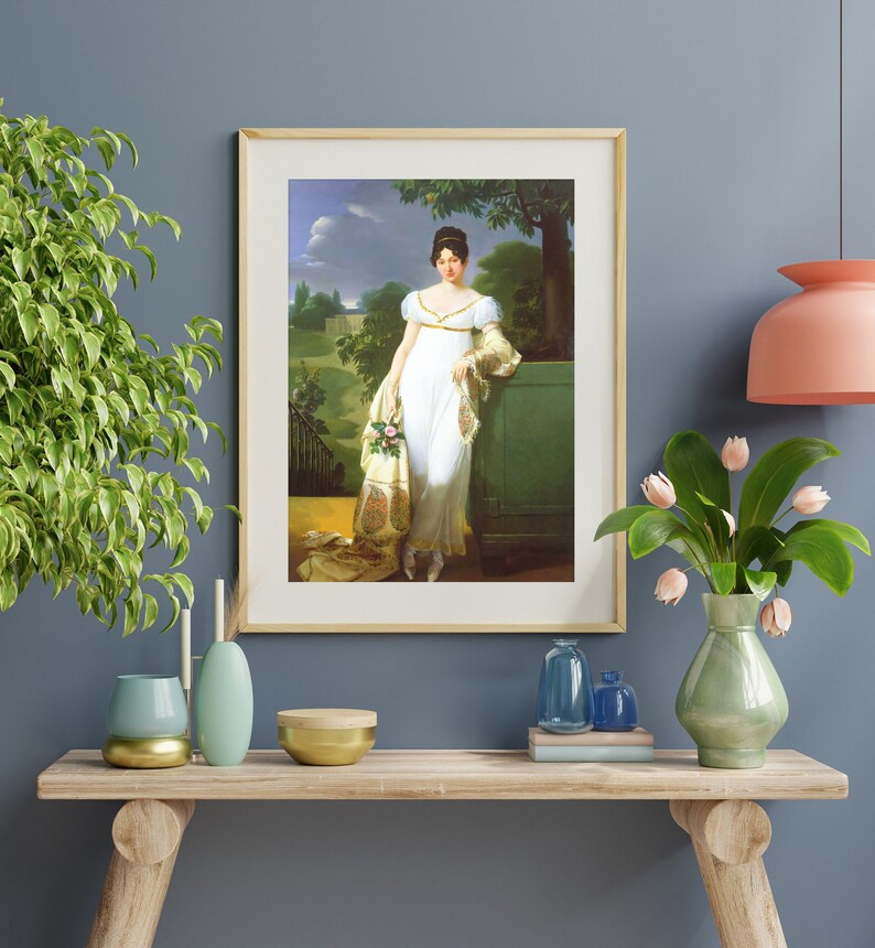 May include: A framed painting of a woman in a white dress standing in a garden setting. She is holding a bouquet of flowers and is looking to the left. The painting is set against a blue wall.