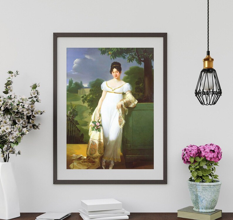 May include: A framed portrait painting of a woman in a white dress with a floral shawl. She is standing in a garden setting with a tree behind her. The painting is in a dark brown frame.