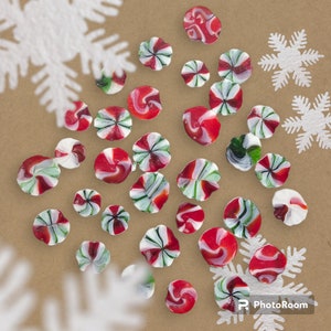 May include: A collection of red and white candy canes arranged on a brown surface with white snowflakes.
