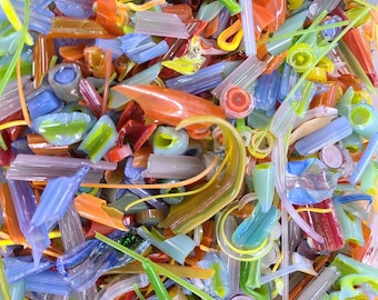 May include: A collection of assorted glass shards and fragments in various shapes and sizes. The pieces feature a vibrant color palette including shades of orange, blue, green, yellow, and purple, with some translucent and opaque textures.