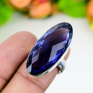 Peut inclure: Une bague en argent avec une grande améthyste facetée de forme ovale. La pierre précieuse est d'une couleur violet foncé.