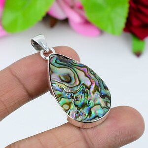 May include: A silver pendant featuring a teardrop-shaped abalone shell with iridescent green, blue, and brown colours.