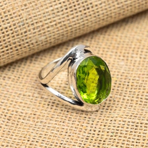 Pode incluir: Um anel de prata com uma grande gema verde oval. O anel tem uma banda única e torcida.