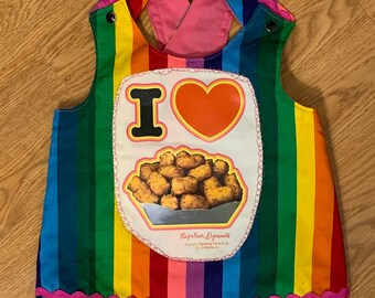 Puede incluir: Un mono de rayas arcoíris con la espalda rosa y un parche en la parte delantera que dice "I ♥ Napoleon Dynamite" con una imagen de tater tots.