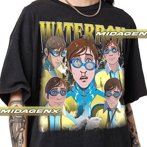 May include: Black t-shirt featuring a graphic of a cartoon character wearing blue goggles and a blue and yellow outfit. The graphic includes the text "WATERBOMB" in yellow block letters. The shirt has a vintage, distressed look.