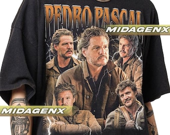 May include: Black t-shirt featuring a graphic of Pedro Pascal with the text "PEDRO PASCAL" in an orange, vintage-style font. The design includes multiple images of the actor, with lightning bolt accents. The brand name "MIDAGENX" is also visible.