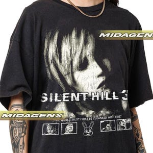 May include: Black t-shirt with a distressed graphic from Silent Hill 3. The design features a woman's portrait and the game's title in white. The text "THE WORLD MUST FIRST BE CLEANSED WITH FIRE" is printed below the title.
