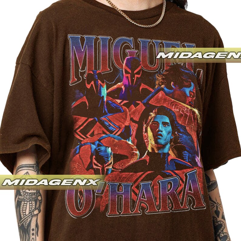Puede incluir: Camiseta marr&oacute;n con un estampado gr&aacute;fico vintage de un grupo de personas, incluyendo un hombre con el nombre "MIGUEL O'HARA" impreso en letras grandes. El gr&aacute;fico est&aacute; en tonos de rojo, azul y negro.