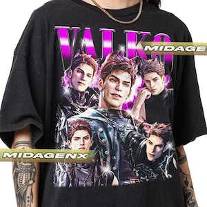 May include: A black short-sleeve t-shirt featuring a graphic print of five identical male figures with cat ears, set against a purple lightning background. The text VALKO is printed in large, bold, metallic-style letters at the top of the design.