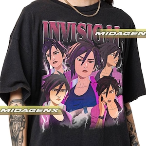 Könnte beinhalten: Dunkelgraues T-Shirt mit einer Grafik einer Figur aus einer Zeichentrickserie. Das Design enthält mehrere Bilder der Figur, mit dem Wort "INVISIG" darüber. Die Figur trägt eine rosa Jacke und ein blaues T-Shirt.