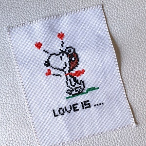 Korsstygnsbroderi av en svartvit valp