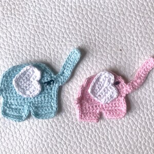 May include: Two crocheted elephants, one light blue and one pink, with white heart-shaped ears.