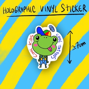 May include: Holographic vinyl sticker featuring a cartoon frog with a blue and red hat, overalls, and a pink tongue. The sticker has the text "Cool Kids Cool Tattoos" and is approximately 2.7 cm in height.