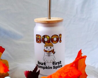 May include: A frosted glass tumbler with a bamboo lid and metal straw. The design features a white ghost wearing a yellow beanie and scarf, holding a coffee cup, with the text BOO! but first pumpkin spice in orange and black.