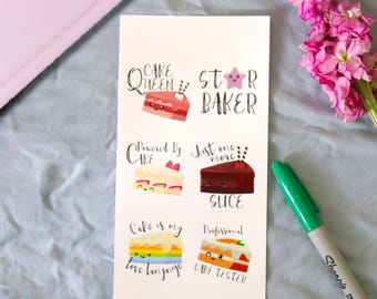 May include: A white card featuring six illustrated cake slices with text: "Cake Queen", "Star Baker", "Powered by Cake", "Just one more slice", "Cake is my love language", and "Professional Cake Tester". A green marker and pink flowers are also visible.
