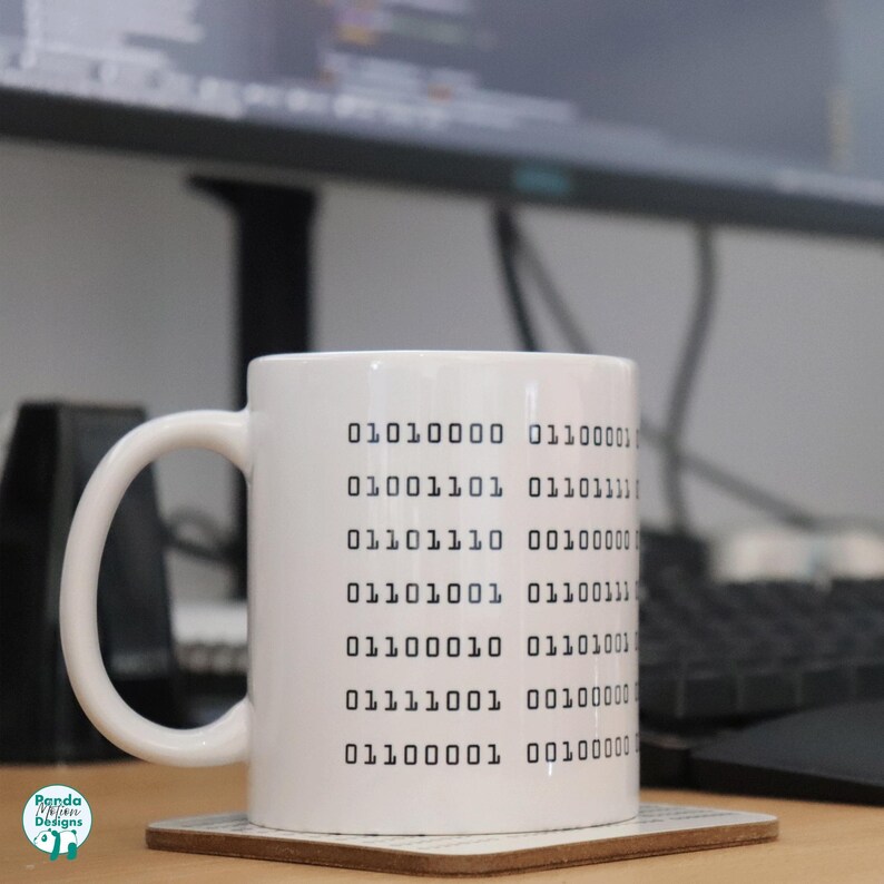 May include: White ceramic mug with black binary code printed on the side. The code reads: 01010000 01100001 01001101 01101111 01101110 00100000 01101001 01100111 011100010 0010 01101001 01111001 00100000 01100001 00100000