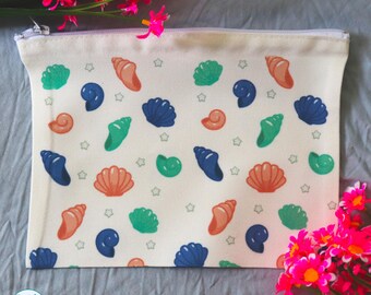 May include: A rectangular off-white canvas zipper pouch featuring a repeating pattern of orange, green, and dark blue seashells interspersed with small gray star shapes. The bottom left corner displays a circular logo with the text Panda Motion Designs.