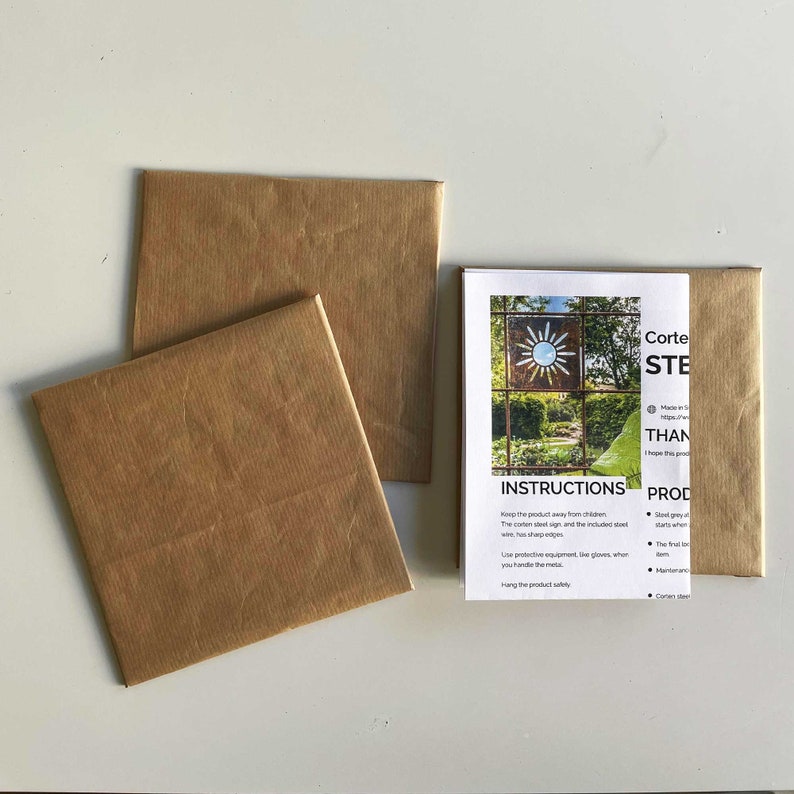 Op de afbeelding: Twee bruine papieren enveloppen en een vel papier met instructies voor een cortenstalen zonneschild. De instructies bevatten informatie over het product, veiligheidsmaatregelen en hoe het schild te hangen.