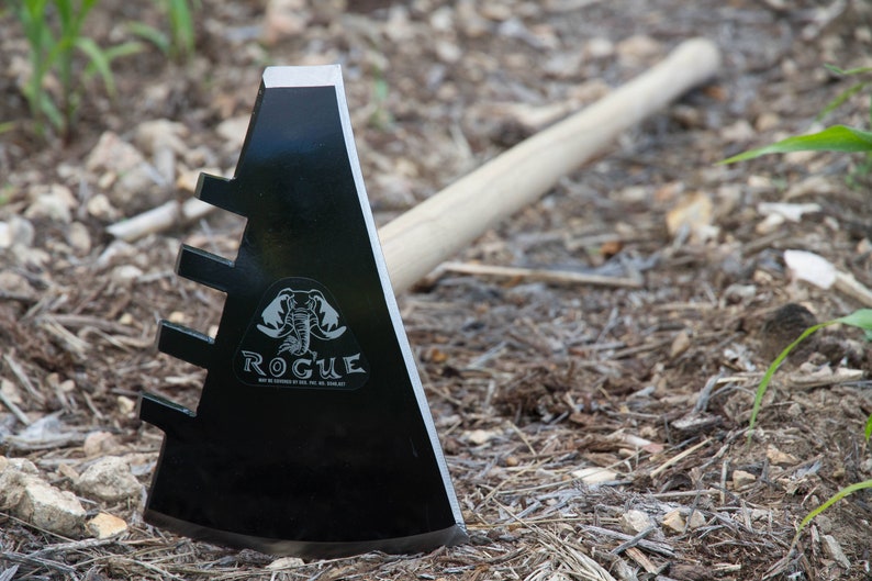 Puede incluir: Una azada de metal negro con mango de madera. La azada tiene una hoja triangular con cinco p&uacute;as en el lateral. La hoja tiene un logotipo que dice "Rogue" con un gr&aacute;fico de elefante.