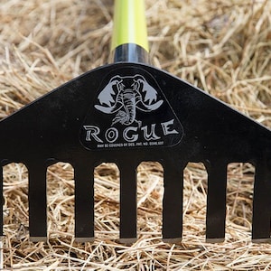 May include: Black metal rake with five tines. The rake has a green handle and a black logo with an elephant and the word "ROGUE" on it. The text "MAY BE COVERED BY DES. PAT. NO. D548,837" is also on the logo.