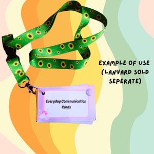 May include: A green lanyard with a sunflower pattern is connected to a stack of Everyday Communication Cards. The cards have a light purple border and white text. The background is a mix of orange, yellow, and green.