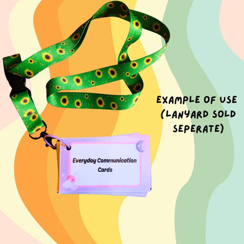 May include: A green lanyard with a sunflower pattern is connected to a stack of Everyday Communication Cards. The cards have a light purple border and white text. The background is a mix of orange, yellow, and green.
