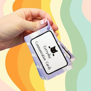 May include: A set of purple and white communication cards with a black cat logo and the text "Everyday Communication Cards". The cards are held together with a purple ring.
