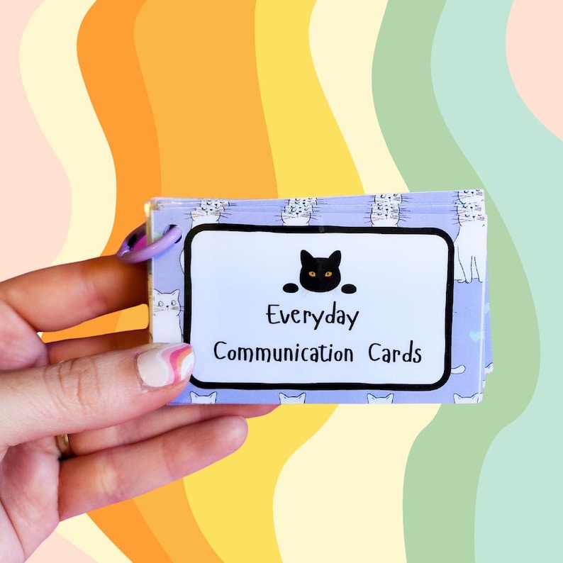May include: A stack of purple and white communication cards with a black cat illustration and the text "Everyday Communication Cards".