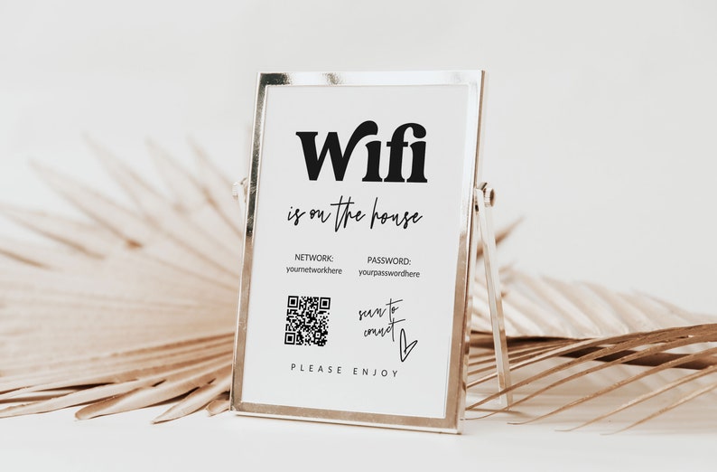 May include: A white sign in a silver frame with the text "Wifi is on the house" and a QR code to connect to the network. The sign also includes the text "NETWORK: youmetworkhere PASSWORD: yourpasswordhere" and "PLEASE ENJOY".