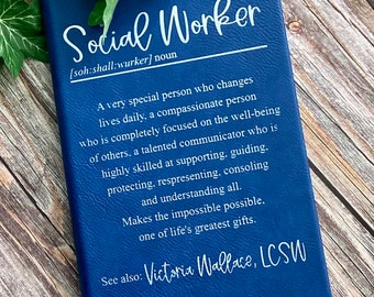 May include: A blue leather-bound journal with the definition of "Social Worker" embossed in white. The text reads: "A very special person who changes lives daily, a compassionate person who is completely focused on the well-being of others. A talented communicator who is highly skilled at supporting, guiding, protecting, representing, consoling and understanding all. Makes the impossible possible. One of life's greatest gifts. See also: Victoria Wallace, LCSW"