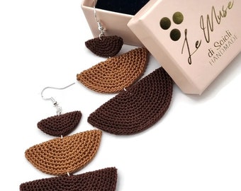 May include: Handmade crochet earrings in shades of brown, displayed with a pink gift box. The earrings feature a layered, crescent moon design. The gift box has gold lettering that reads "Le Muse di Seicli HANDMADE".