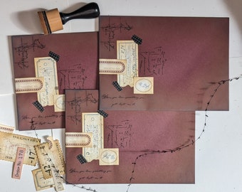 May include: Three burgundy envelopes with decorative paper scraps and handwritten text. The text on the envelopes reads "When you lose something you get lost in it".
