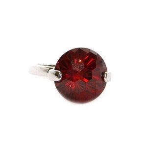 May include: A silver ring with a large, round, red gemstone.