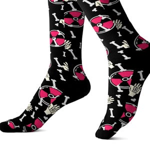May include: Black socks with a repeating pattern of pink radiation symbols, white bones, and the letter "I". The socks are knee-high and made of a stretchy material.