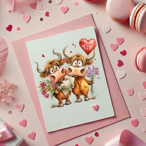 Pu&ograve; includere: Un biglietto di San Valentino con due mucche delle Highlands dei cartoni animati che tengono fiori e una lettera. Un palloncino rosso a forma di cuore con la scritta "YOU" fluttua sopra. Sfondo rosa con coriandoli e macarons a forma di cuore.