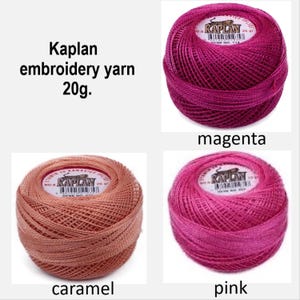 Può includere: Quattro rocchetti di filo da ricamo Kaplan in magenta, caramello e rosa. Il testo "Kaplan filo da ricamo 20g" è visualizzato in alto. Ogni rocchetto è etichettato con il suo colore. Il filo è ben avvolto.