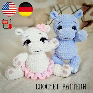 Op de afbeelding: Haakpatroon voor twee amigurumi-nijlpaarden. Eén nijlpaard is wit met een roze tutu en een roze bloem op zijn hoofd. Het andere nijlpaard is lichtblauw. Beide nijlpaarden hebben zwarte ogen en een zwarte neus.