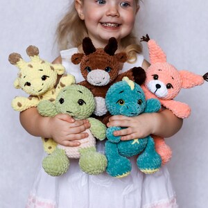 May include: A young child is holding a collection of crocheted stuffed toys. The toys include a giraffe, a bull, a dinosaur, and a squirrel. The toys are all made with soft, colourful yarn.