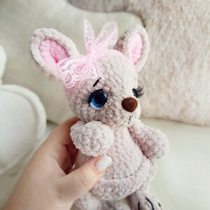 May include: A handmade plush mouse in soft grey with pink inner ears and a pink lace bow. The mouse has blue eyes, long eyelashes, and a brown nose. The toy is a cute, cuddly design.
