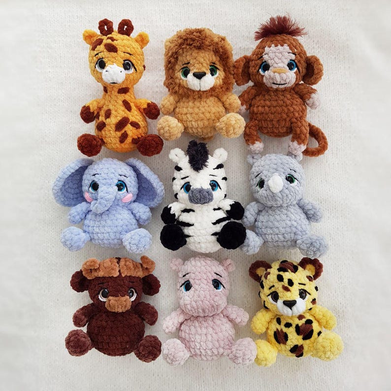 May include: A collection of eight crocheted stuffed animals, including a giraffe, lion, monkey, elephant, zebra, rhino, hippopotamus, and leopard. The animals are all different colors and have various facial expressions.