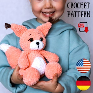May include: A crochet pattern for a plush fox toy. The pattern is available as a PDF download. The image shows a child holding the finished toy, which is peach-coloured with a white belly and brown ears.