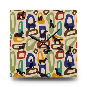 Op de afbeelding: Vierkante wandklok met een herhalend patroon van zwarte honden silhouetten op een crèmekleurige achtergrond. De honden staan tegen kleurrijke abstracte vormen in rood, blauw, groen en geel. De klokwijzers zijn zwart.