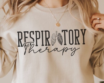 May include: A beige sweatshirt with the text "RESPIRATORY therapy" in black lettering. The text is accompanied by a graphic of a pair of lungs.